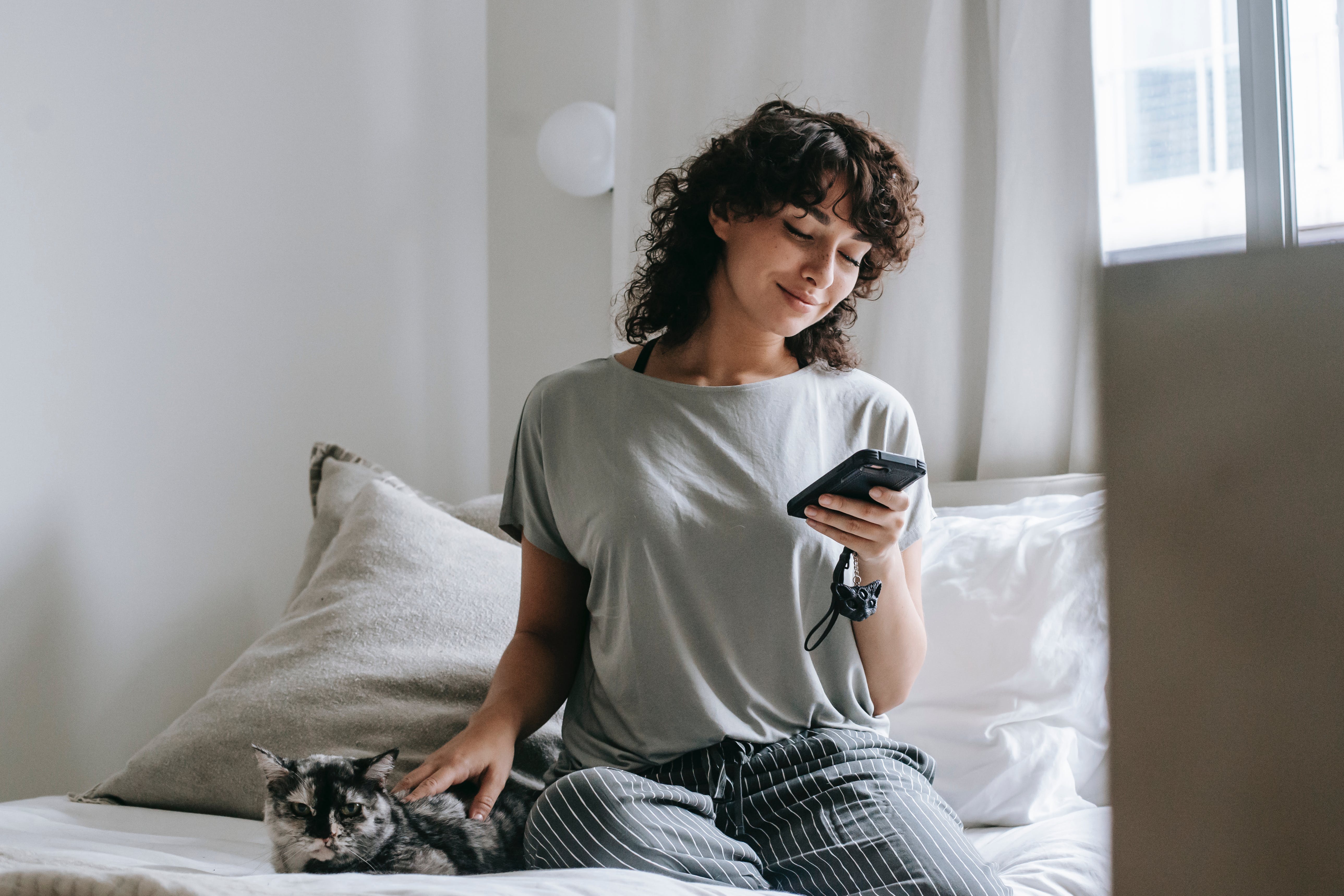 Woman petting a cat on a bed